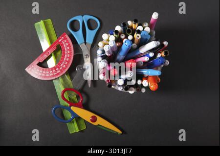 Pens pens pencils ruler and scissors in a plastic jar on a dark background Stock Photo