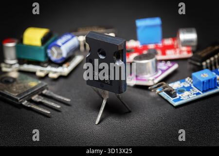 A close-up of a powerful MOSFET transistor in a TO-247 case surrounded by various radio components on a dark background Stock Photo