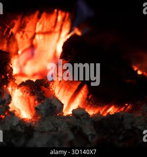 Close-up of glowing embers and burning wood in a fireplace. Scene captures the warmth and light of a cozy fire Stock Photo