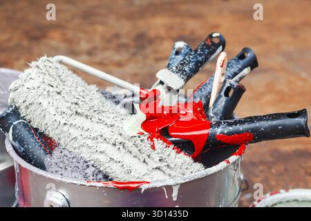 Empty paint buckets containing used rollers and brushes. Stock Photo