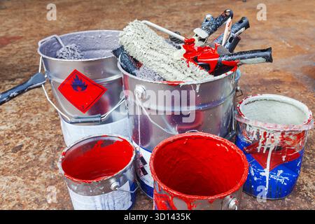Empty paint buckets containing used rollers and brushes. Stock Photo