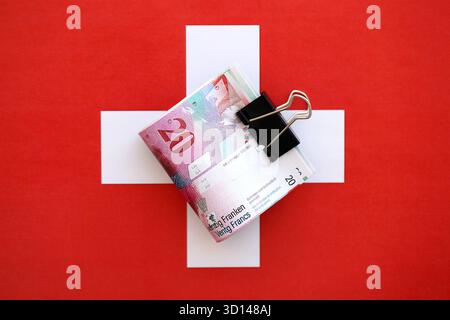 Swiss franc banknotes and flag. The current francs money bills lies on flag in big amount. The concept of business in Switzerland Stock Photo