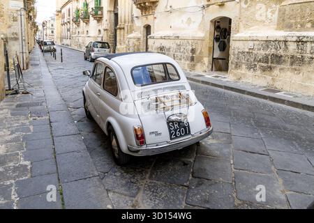Noto, Sizilien - Italy - 04-06-2025: Rear view of a vintage Fiat 500 parked on a cobblestone street with historic buildings in the background. Capture Stock Photo
