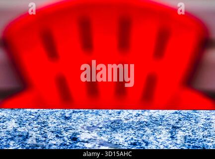A ceramic table top with a red chair in the background Stock Photo