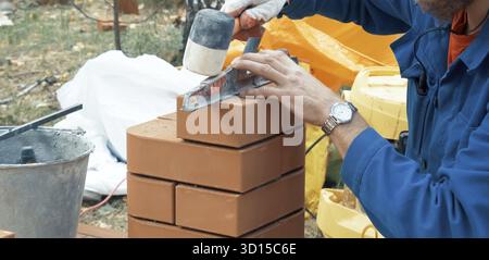 A man builds a brick wall. Brick put on the solution. Construction of a brick house Stock Photo