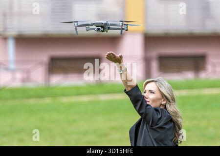 Drone takes off from hands of young blonde woman, modern technology concept Stock Photo