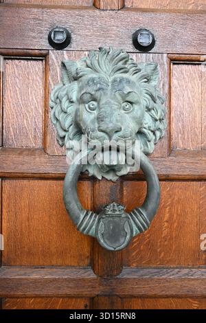 Metal lion head and ring door knocker or handle on wooden door Stock Photo