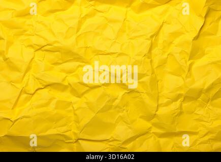 Crumpled yellow paper forms an abstract textured background, showcasing a captivating visual with its intricate folds and wrinkles, creating a unique Stock Photo