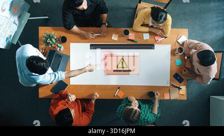 A diverse group of professionals engages in a meeting, focusing on a cybersecurity alert displayed on a screen, highlighting the importance of collabo Stock Photo