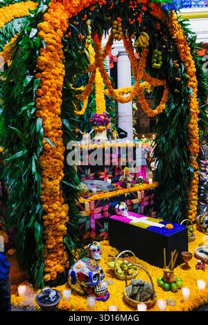 Colorful Day of the Dead altar decorated with marigolds, sugar skulls, food offerings and candles during a cultural celebration Stock Photo