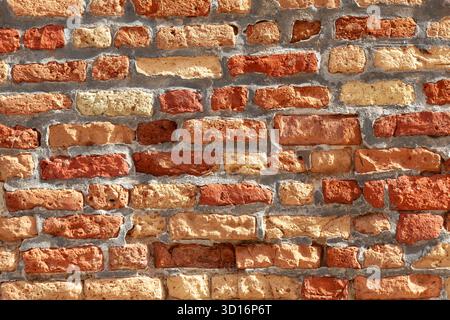 Wall texture of old weathered Venetian red clay bricks exposed to elements, Venice, Italy, urban decay, erosion Stock Photo