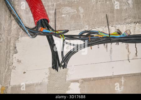 Electric power cables installation on new house construction site wall Stock Photo