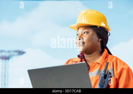 Smiling offshore platform crew member configuring boat management systems for more efficient oil extraction. Happy woman working on drilling rig doing seabed analysis using laptop Stock Photo