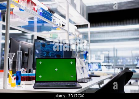 Green screen laptop and computer monitor in laboratory showing 3D molecular model visualization used for research. Mockup notebook and PC in medical lab displaying DNA data Stock Photo