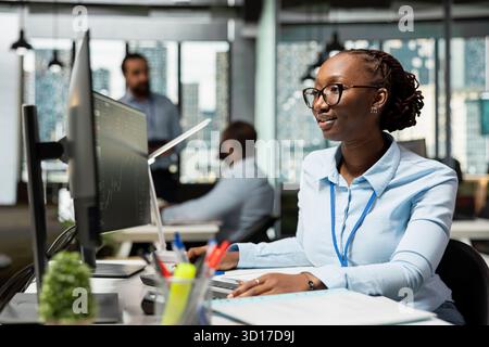 Risk analyst in office using PC to evaluate trading strategies, minimizing losses. African american woman in prop firm using data reports to assess volatility in financial markets Stock Photo