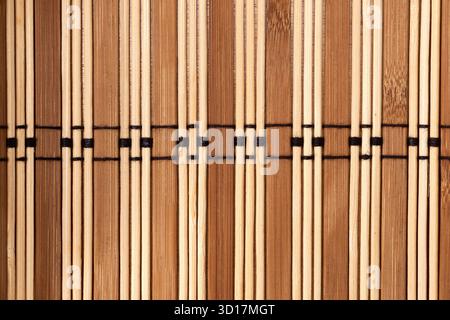A close-up view of intertwined bamboo and wood strips shows a natural pattern. The arrangement showcases a blend of light and dark colors, creating an Stock Photo