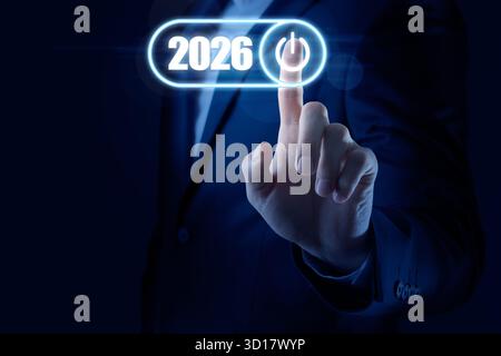 Businessman activating 2026 year by pressing power symbol on virtual screen against dark blue background, closeup. Ready for new year Stock Photo