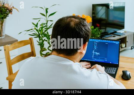 A man sits at a laptop and uses AI, seen from behind. High quality photo Stock Photo