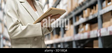 asian female business owner using digital tablet check amount of stock product inventory on shelf at distribution warehouse factory.logistic business Stock Photo