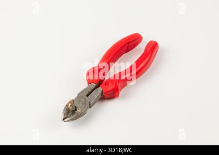 A wire cutting tool with red handles rests on a smooth white surface. The cutting edges show wear, indicating regular use in various projects or repai Stock Photo