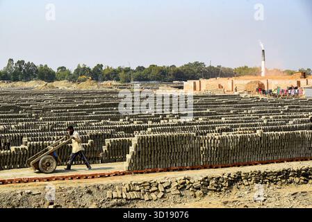 Industrial Brick Yard With Stacks Of Bricks And A Worker Pushing A Wheelbarrow Stock Photo