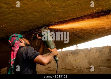 Construction Worker Uses Grinder to Cut Metal, Sparks Flying Under a Concrete Roof Stock Photo