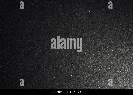 Black glitter texture illuminated from lower right, abstract surface detailed with countless sparkles resembling starlight fading smoothly into dark d Stock Photo