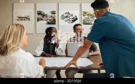 A group of diverse young professionals working together on a project in an architectural firm. The team is actively engaged in planning and discussing Stock Photo