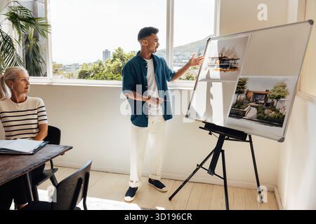 A young male architect shows design concepts on a whiteboard to a senior female colleague in a bright and modern office environment, reflecting creati Stock Photo