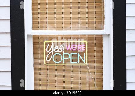 Neon "Yes! We're Open" sign on bamboo-covered window Stock Photo