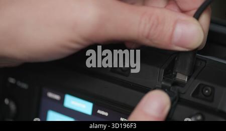 Hand actively connecting a usb-c cable into black tech equipment Stock Photo
