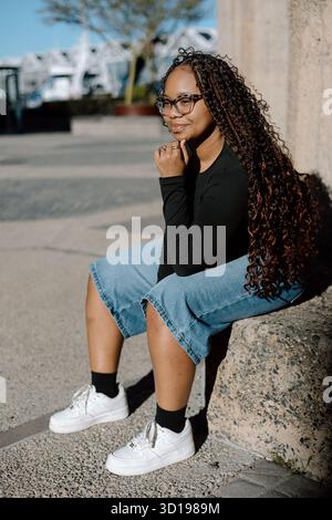 Young woman sitting outside in sunlight Stock Photo
