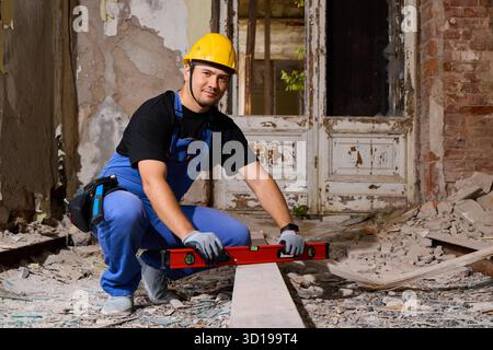 Construction worker measuring a wooden beam in a renovation site Stock Photo