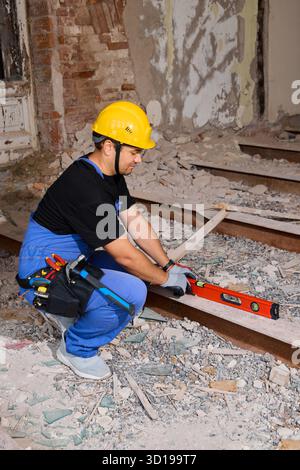 Construction worker levels flooring in an old building renovation Stock Photo