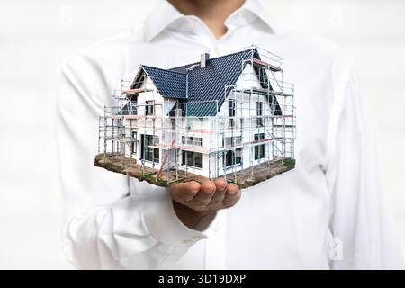 Person holding a scale model of a house under construction Stock Photo