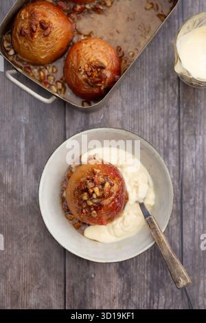 Baked apples in a tin and in a bowl, served with vanilla custard Stock Photo