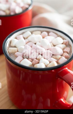 Hot chocolate drink with marshmallows in red mug on wooden table Stock Photo