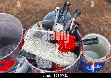 Empty paint buckets containing used rollers and brushes Stock Photo