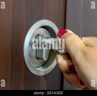 A woman's hand locks the door behind her. A safety precaution for those left alone in the house. Stock Photo