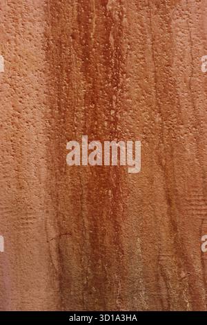 Stained wall, vertical dirty streaks. A damp, orange, red, abandoned wall with stains and streaks. Stock Photo