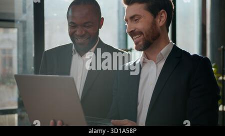 Two multiracial business men team with laptop partnership businessmen working together in office Caucasian man talking to African American male Stock Photo