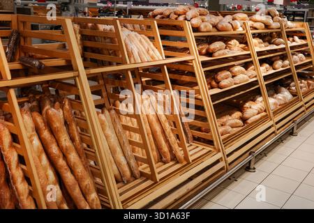 Bakery with a variety of breads on display. The breads are arranged in wooden racks and there are many different types of breads to choose from Stock Photo