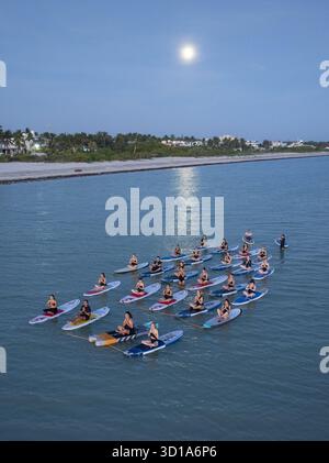 Aerial view of people doing yoga on paddle boards in the water under the moonlight, Progreso, Yucatan, Mexico. Stock Photo