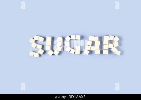 Arrangement of white sugar cubes forming the word 'sugar' on light blue background. Stock Photo