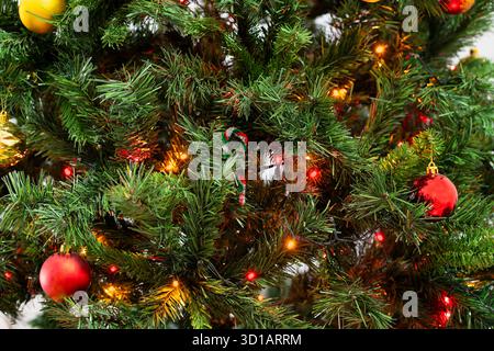 Pattern with green branches with pine needles illuminated. Texture of coniferous tree decorated garlands lights. Christmas holidays backdrop soft focu Stock Photo