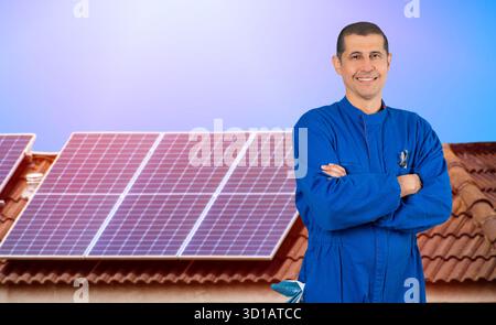 Solar panels,engineer installing standing on the rooftop with solar panels and smiling at the camera. Stock Photo