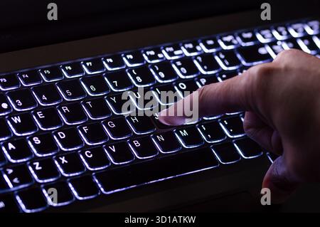 Working on a blue neon computer keyboard with colored backlighting. Computer video games, hacking, technology, internet concept. Selected focus. Stock Photo