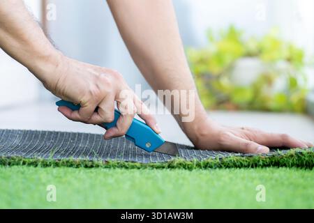 Close-up of man hand cutting and installing artificial grass Stock Photo