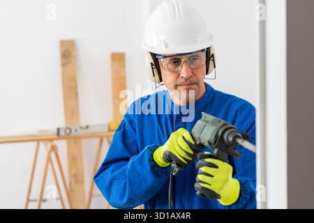 Construction worker working wrecking wall using rotary hammer in a building under renovation Stock Photo