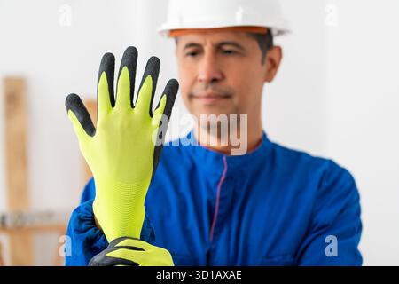 Construction worker putting protective yellow glove before work in a house under reform Stock Photo